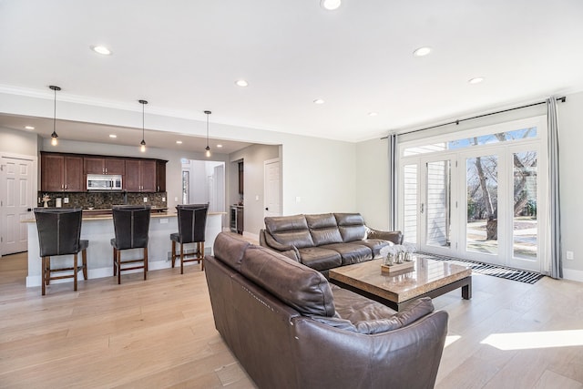 living area featuring recessed lighting, ornamental molding, and light wood finished floors