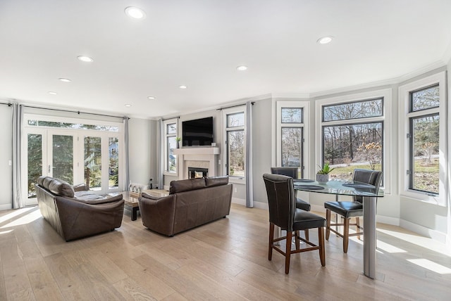 living room with recessed lighting, a glass covered fireplace, and light wood-style flooring