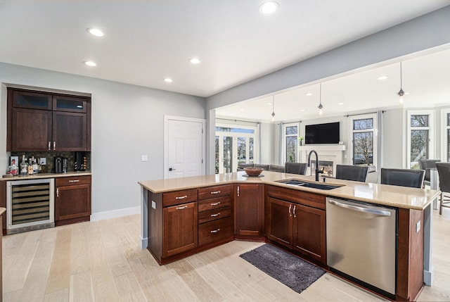 kitchen featuring light wood-style flooring, a sink, stainless steel dishwasher, open floor plan, and wine cooler