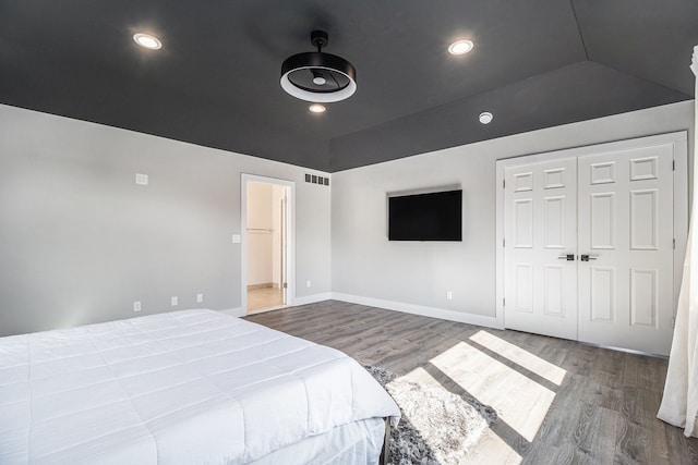 bedroom featuring visible vents, baseboards, lofted ceiling, and wood finished floors