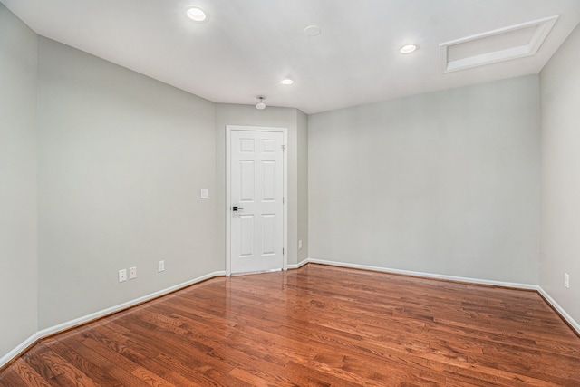 unfurnished room with recessed lighting, baseboards, attic access, and wood finished floors