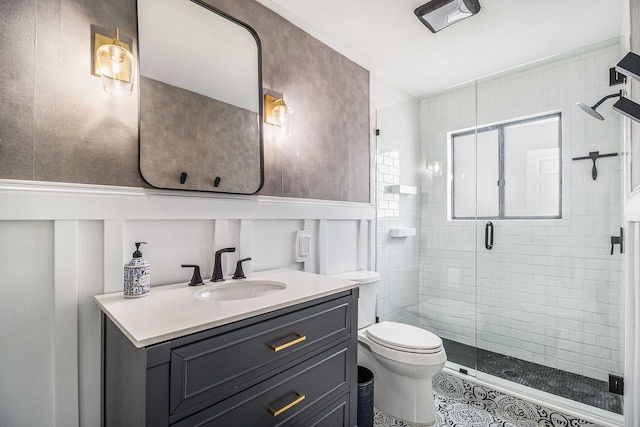 full bath with a shower stall, a wainscoted wall, toilet, a decorative wall, and vanity