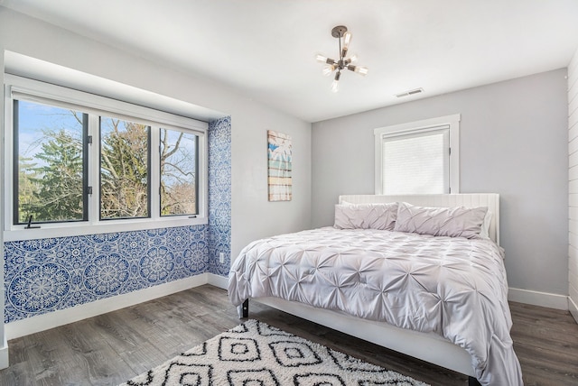 bedroom featuring visible vents, multiple windows, baseboards, and wood finished floors