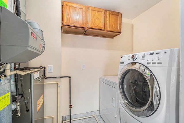 clothes washing area featuring washer and dryer, cabinet space, and light tile patterned floors