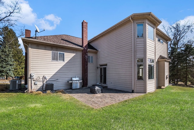 rear view of house featuring a lawn, a chimney, and a patio area