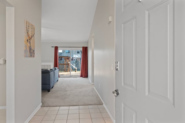 corridor with light tile patterned floors, light colored carpet, and baseboards