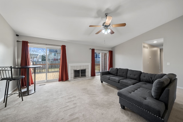 carpeted living area with visible vents, baseboards, vaulted ceiling, a fireplace, and a ceiling fan