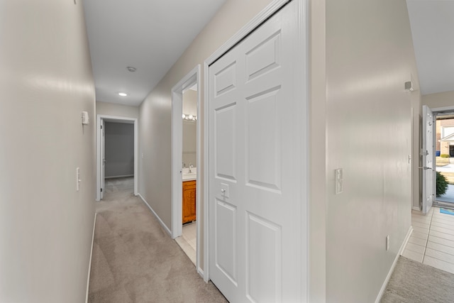 hallway with baseboards and light carpet