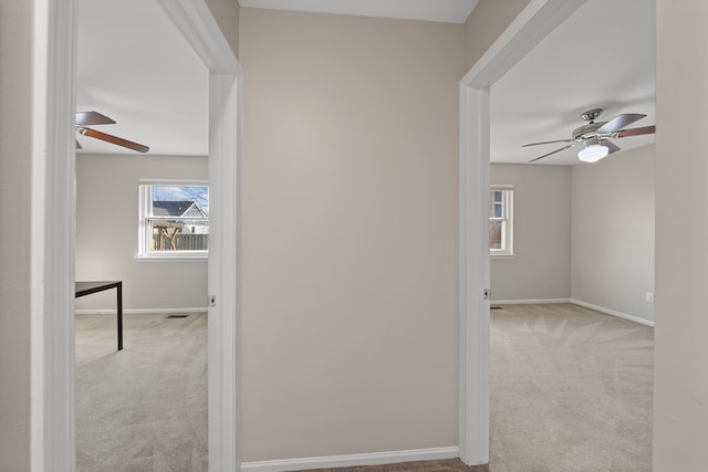 hallway featuring carpet flooring, visible vents, and baseboards