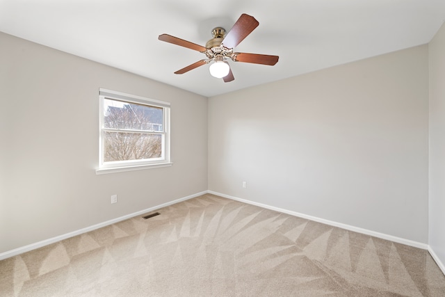 carpeted spare room with visible vents, ceiling fan, and baseboards