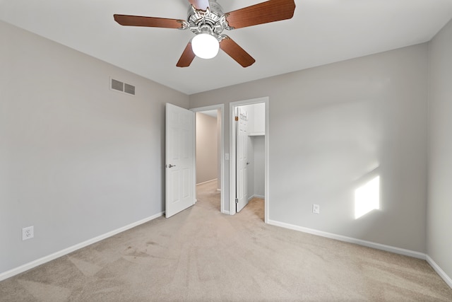 unfurnished bedroom with visible vents, light carpet, baseboards, ceiling fan, and a spacious closet