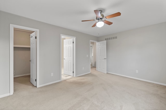 unfurnished bedroom featuring a spacious closet, visible vents, carpet flooring, and baseboards