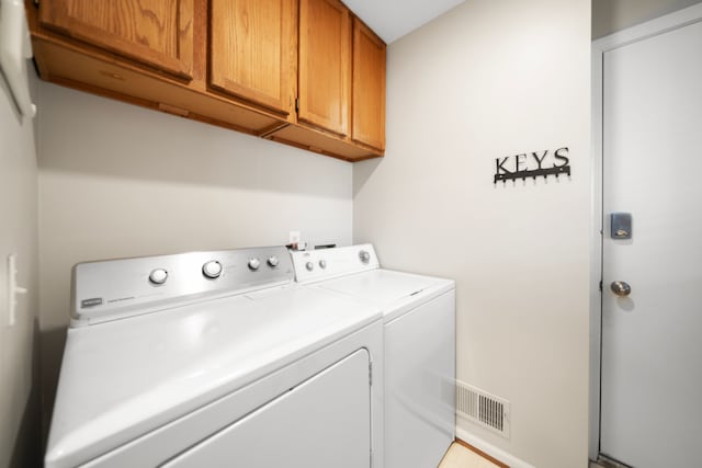 laundry room featuring visible vents, cabinet space, and separate washer and dryer