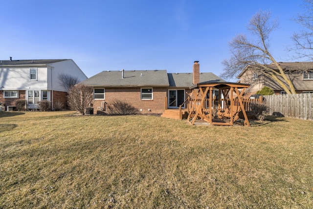 rear view of property with brick siding, a shingled roof, fence, a lawn, and a chimney