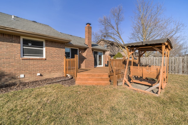 exterior space featuring a deck, fence, a yard, crawl space, and brick siding