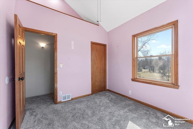 unfurnished bedroom featuring visible vents, lofted ceiling, baseboards, and carpet flooring