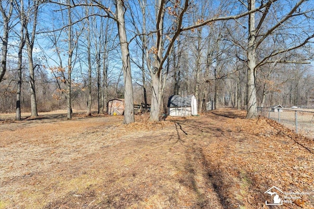 view of yard with an outdoor structure, a storage unit, and fence