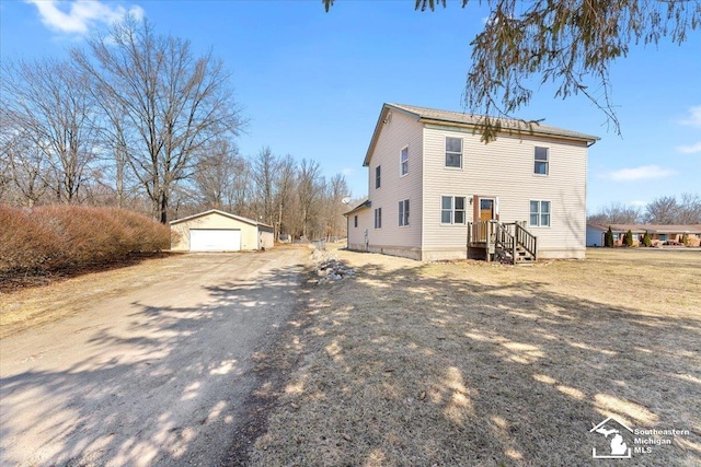 back of house featuring a detached garage, an outbuilding, and driveway