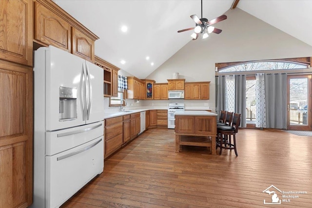 kitchen with white appliances, hardwood / wood-style flooring, open shelves, and a sink