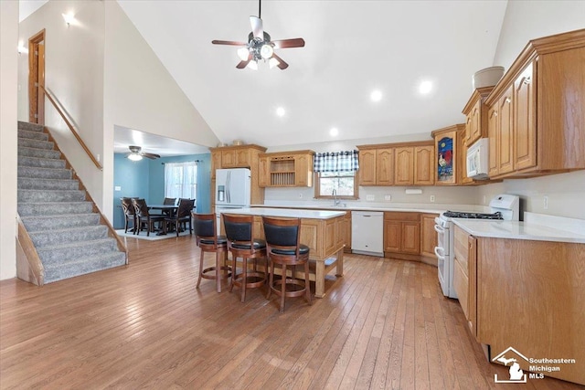 kitchen with light wood finished floors, a healthy amount of sunlight, white appliances, and a kitchen island