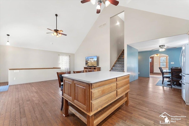 kitchen with visible vents, open floor plan, light countertops, hardwood / wood-style floors, and arched walkways