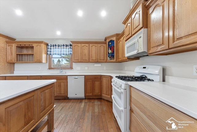 kitchen with light wood finished floors, a sink, light countertops, white appliances, and open shelves