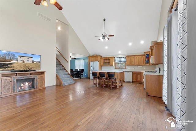 kitchen with visible vents, a glass covered fireplace, white appliances, light countertops, and ceiling fan