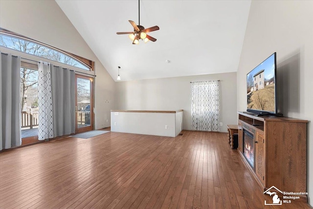 unfurnished living room featuring a glass covered fireplace, high vaulted ceiling, hardwood / wood-style floors, and ceiling fan