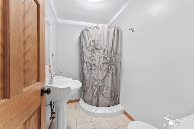 bathroom featuring tile patterned floors, baseboards, a shower stall, and a sink