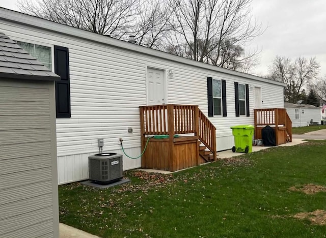 rear view of house with central AC unit and a yard