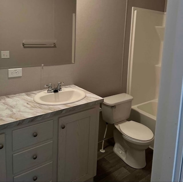 bathroom with toilet, vanity, and wood finished floors