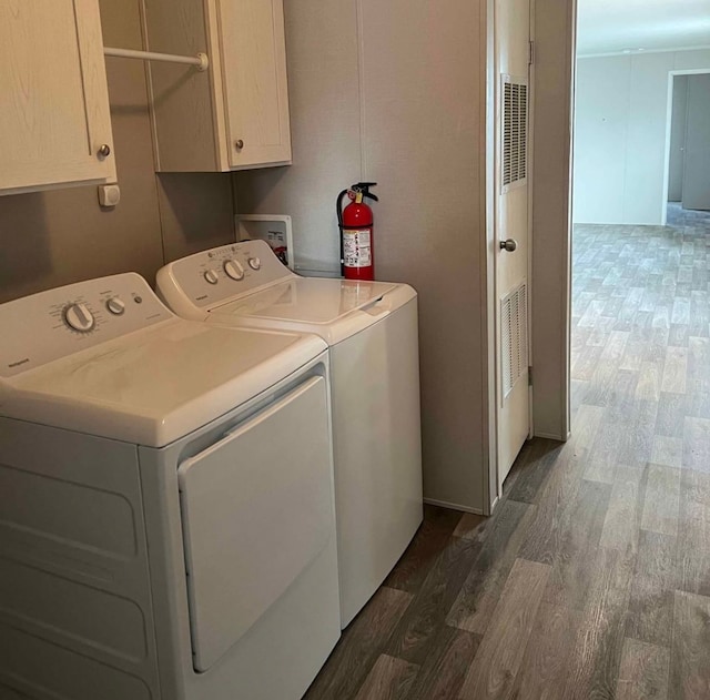 clothes washing area with washer and dryer, dark wood-type flooring, and cabinet space