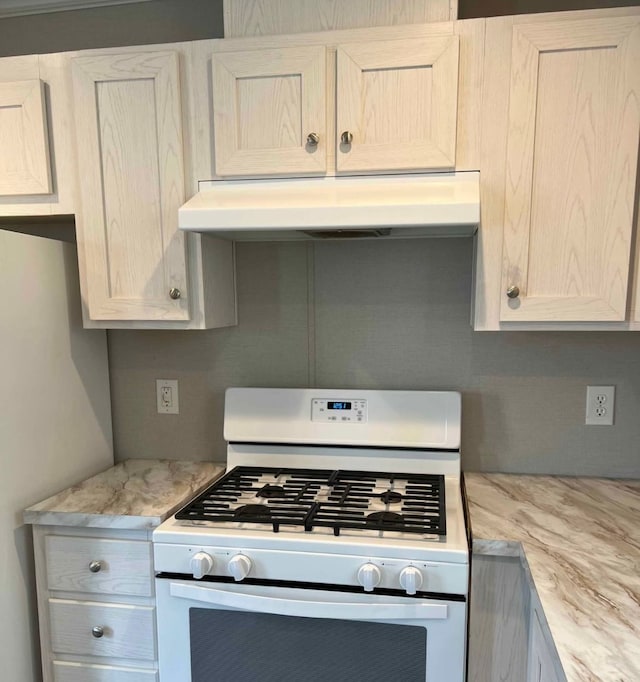 kitchen featuring under cabinet range hood, white appliances, and light stone counters