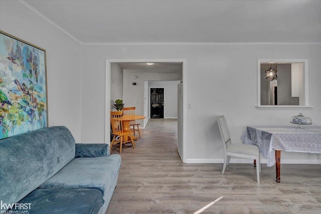 living area with wood finished floors, baseboards, and ornamental molding