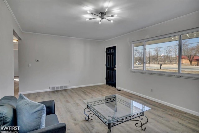 living area with light wood finished floors, visible vents, baseboards, and ornamental molding