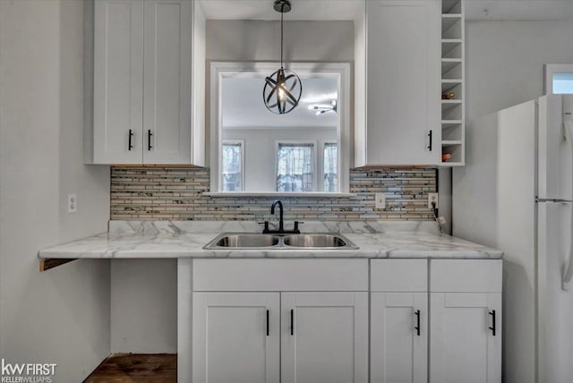 kitchen featuring a sink, white cabinetry, tasteful backsplash, and freestanding refrigerator