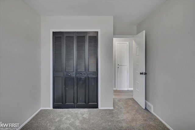 unfurnished bedroom with a closet, visible vents, baseboards, and carpet floors