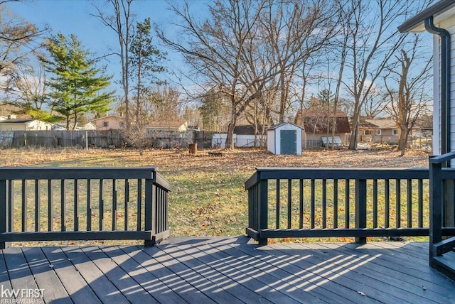 wooden terrace with a storage unit, an outbuilding, a fenced backyard, and a lawn