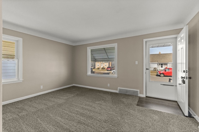 foyer with visible vents, baseboards, and dark carpet