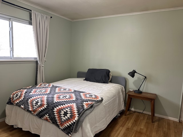 bedroom with ornamental molding, baseboards, and wood finished floors