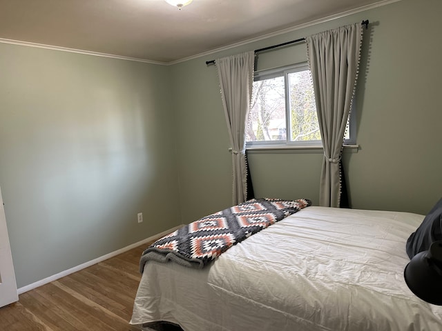 bedroom featuring baseboards, wood finished floors, and ornamental molding