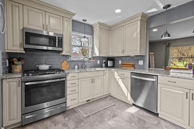kitchen with a sink, tasteful backsplash, cream cabinetry, and stainless steel appliances