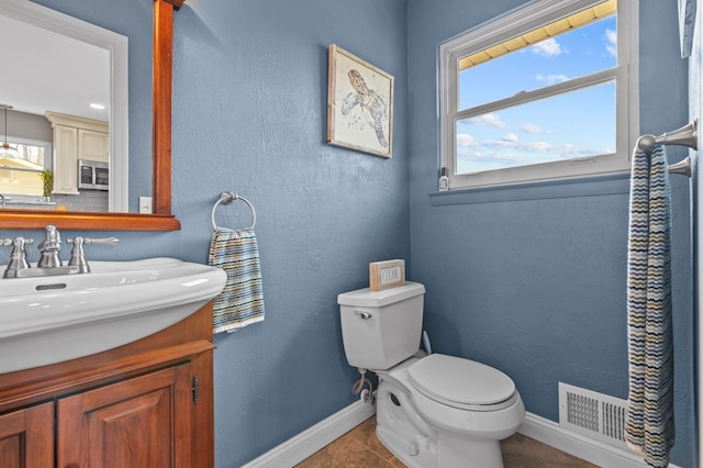bathroom featuring toilet, baseboards, visible vents, and vanity