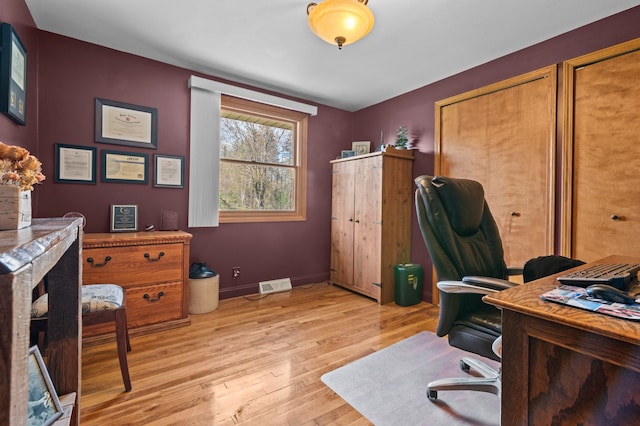 office space featuring baseboards, visible vents, and light wood-style floors