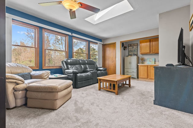 living area featuring a skylight, plenty of natural light, light carpet, and a ceiling fan