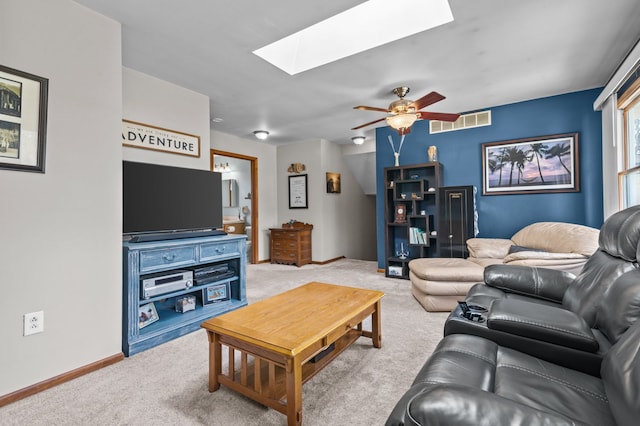 living room featuring a ceiling fan, a skylight, visible vents, and carpet