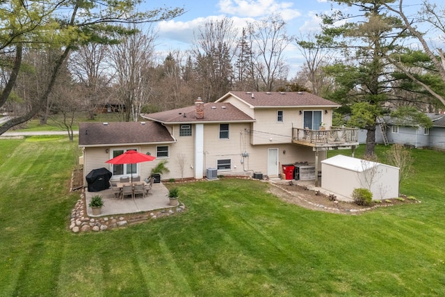 rear view of property with a yard, a chimney, an outbuilding, a patio area, and a storage shed