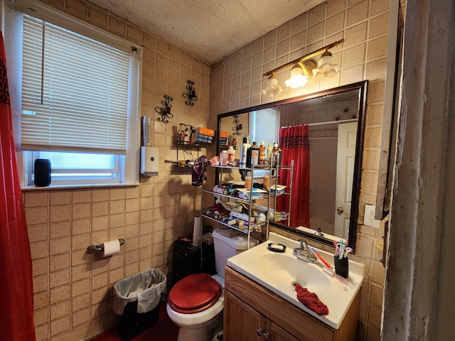 full bath featuring toilet, curtained shower, a textured ceiling, tile walls, and vanity