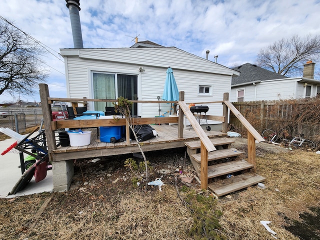 rear view of house featuring a deck and fence