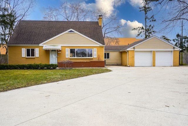 view of front of home with a front yard, driveway, a chimney, a garage, and brick siding